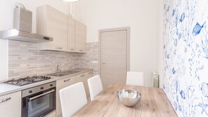 Una cucina moderna con piano cottura a gas, forno e mobili bianchi. C'è un tavolo da pranzo con sedie e una ciotola sopra.