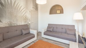 Un soggiorno moderno con due divani grigi, un pavimento in legno, un grande murale e un lampadario.