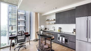 A modern kitchen with a large island, dark cabinetry, and a view of a cityscape through large windows.