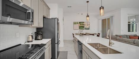 A modern kitchen with stainless steel appliances, a large island with a sink, and pendant lighting.