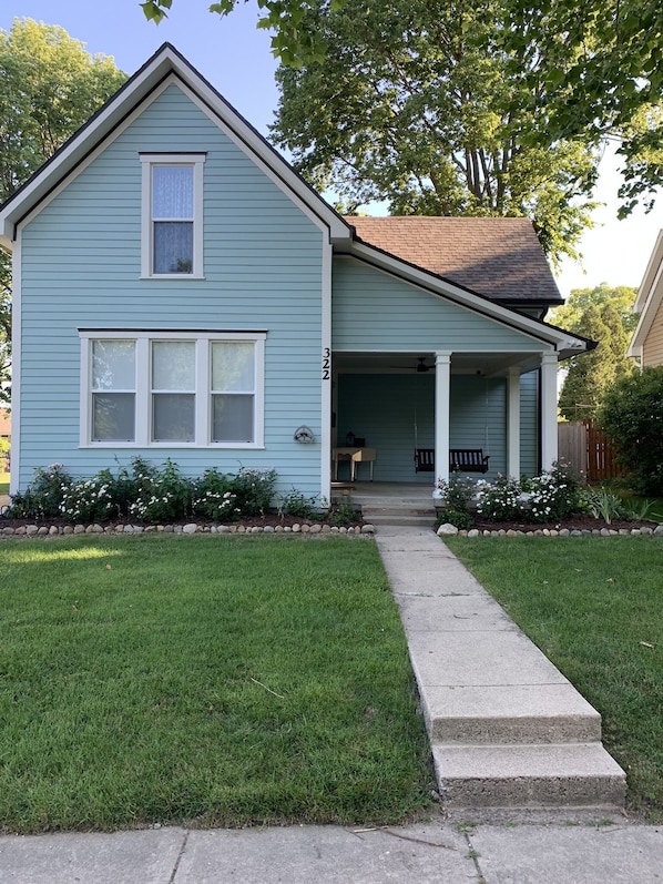 A light blue single-story house with a front porch, a number '322' on the side, and a well-maintained lawn. - Super Charming Modern Cottage (Pendleton)