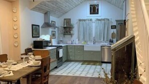 Une cuisine compacte avec un coin repas, un ventilateur de plafond et une vue sur le salon.
