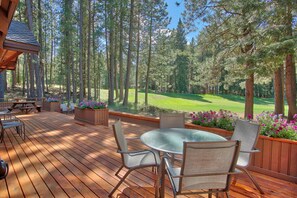 Eine Holzterrasse mit Sitzgelegenheiten im Freien mit Blick auf einen Golfplatz.