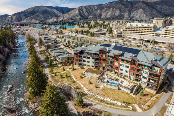 A modern hotel with multiple floors, a swimming pool, and a river nearby. - Modern Villa - walk to lift, Westin amenities! Pool, hot tub, fire pit, ski valet, ski shuttle (Avon)