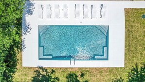 Vista aérea de una piscina con múltiples sillas de descanso y una superficie de agua azul cristalina.