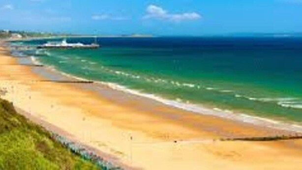 A beach with clear turquoise water, a sandy shore, and a boat in the distance. - Luxury 3-bed Penthouse Apartment in Bournemouth (Bournemouth)
