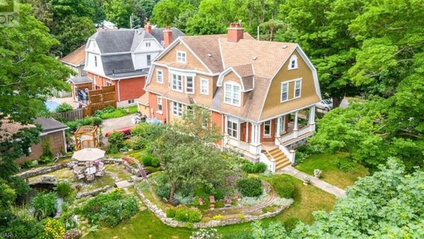 A large, two-story house with a well-maintained garden and a small pond. - Eddie Manor: 1907 Gem in Downtown Meaford (Meaford)