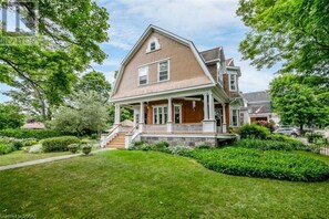 A two-story house with a front porch, a stone foundation, and a well-maintained lawn. - Eddie Manor: 1907 Gem in Downtown Meaford (Meaford)