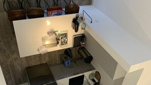 Een compacte keuken met een wit aanrecht, een ingebouwde oven en een magnetron. Er staan stoelen bij een kleine tafel, waarop een doos Fortnite staat.