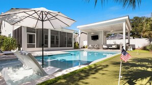 A swimming pool with a slide, a covered patio area, and an American flag. - Posh Home + Private Pool, LSV, Putt & Basketball (Seacrest)