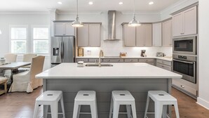 A modern kitchen with a large island, stainless steel appliances, and pendant lighting. - Posh Home + Private Pool, LSV, Putt & Basketball (Seacrest)