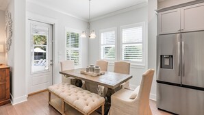 A modern kitchen with a stainless steel refrigerator, a wooden dining table with four chairs, and a bench. - Posh Home + Private Pool, LSV, Putt & Basketball (Seacrest)