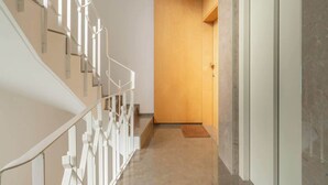 Un interior moderno con una escalera, una puerta de madera y un piso de mármol.