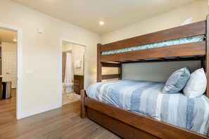 Une chambre avec un lit superposé en bois, une salle de bain avec douche et un petit coin cuisine.