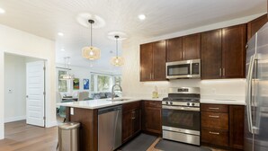 A modern kitchen with dark wood cabinets, stainless steel appliances, and a central island. - Brand New Luxury Condo/Mountain Views/Shared Hot Tub (Keystone)