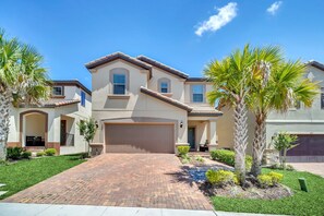 A two-story house with a brick driveway, palm trees, and a garage. - Modern and Colorful Home! Spiderman, Princess and Mickey Themed Rooms & Perfect Movie/game Room! (Kissimmee)