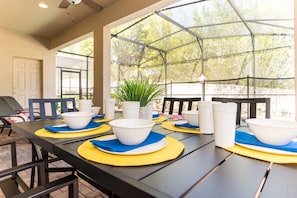Enjoy meals al fresco in this outdoor dining area with a long table and comfortable seating.