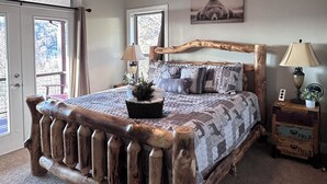 A bedroom with a large bed, a ceiling fan, a window, and a door. - Spacious Smoky Mountain Getaway - Sleeps 10, Game Room, Firepit & Views (Maggie Valley)