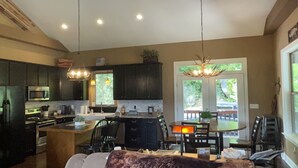 A modern kitchen with dark cabinets, stainless steel appliances, and pendant lighting. - Spacious Smoky Mountain Getaway - Sleeps 10, Game Room, Firepit & Views (Maggie Valley)
