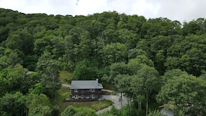 A two-story house surrounded by dense forest. - Spacious Smoky Mountain Getaway - Sleeps 10, Game Room, Firepit & Views (Maggie Valley)
