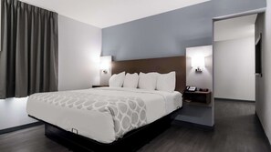 A modern hotel room with a large bed, bedside tables with lamps, and a view of the hallway.