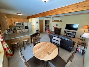 Cozy living space with a kitchen and seating area, featuring a dining table, sofa, and TV.
