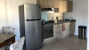 Eine moderne Küche mit Edelstahlkühlschrank, Holzschränken, einem Gasherd und einem Spülbecken.