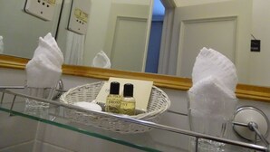 A bathroom with a glass partition, a mirror, a basket with toiletries, and a towel dispenser. - Lansdowne hotel (Royal Leamington Spa)