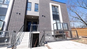 A modern two-story building with a brick facade, large windows, and a visible staircase leading to the entrance.