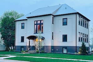 A large, modern two-story building with a symmetrical facade, large windows, and a central entrance with steps.