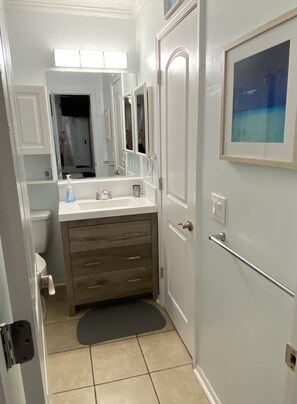 Un baño con un lavabo blanco, un espejo, un inodoro y una puerta con manija.