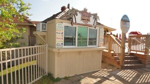 Ein Kiosk direkt am Strand mit Schild, Holzterrasse und umzäunter Fläche.