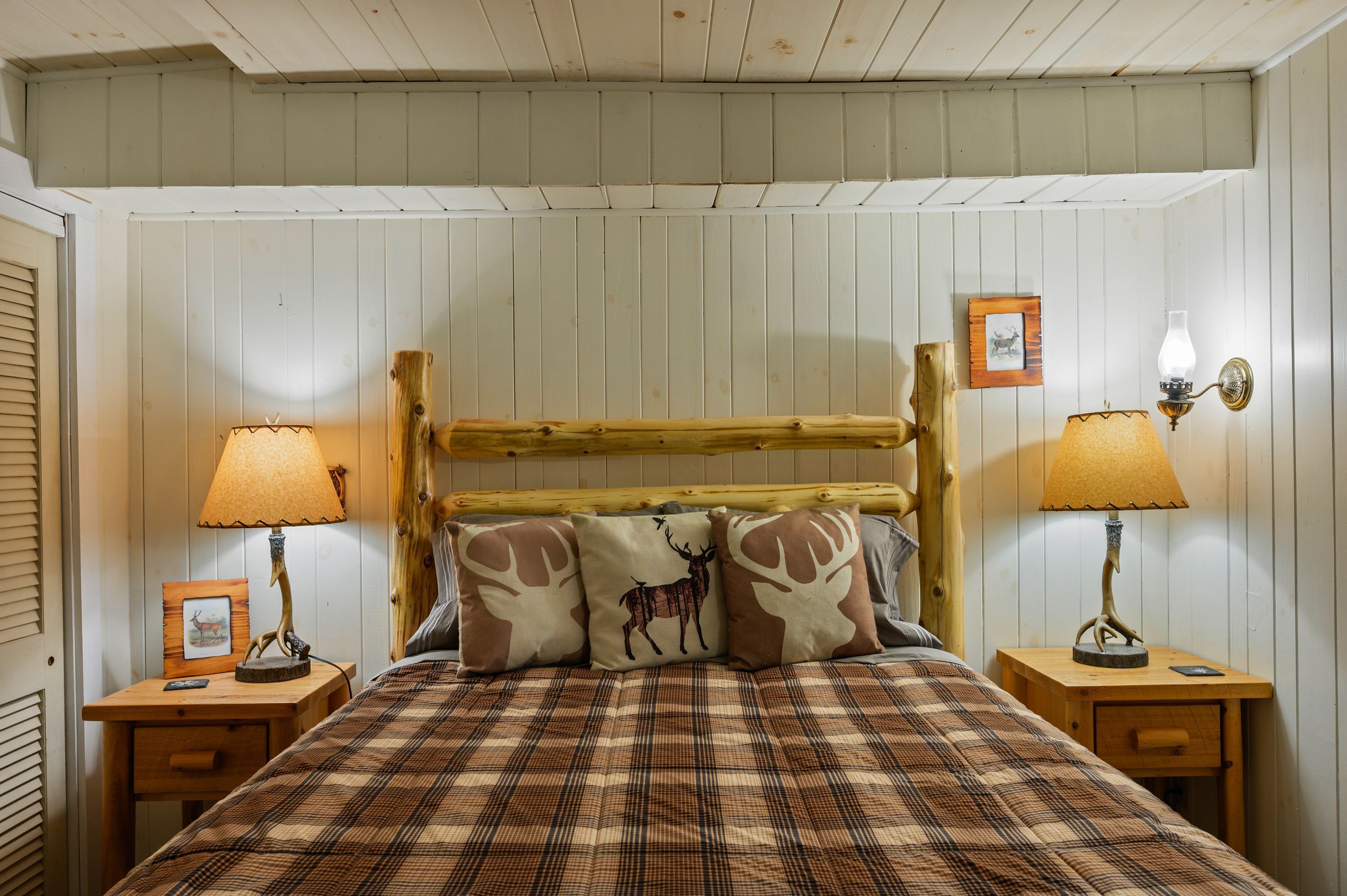 Ein Bett mit karierter Tagesdecke, zwei Nachttische mit Lampen und ein Holzkopfteil.