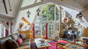 A cozy interior with a stone fireplace, leather sofa, wooden furniture, and large windows. - Mtn VIEWS, 4 bedrooms, hot tub, Arcade games, close to Ober + Gatlinburg (Gatlinburg)