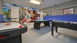 Une table de billard, une table de baby-foot, une fresque représentant des super-héros et un panneau encadré portant le numéro 15.