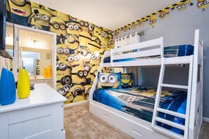 Ein Stockbett mit einer Wand im Minion-Design, eine weiße Kommode und ein Spiegel.