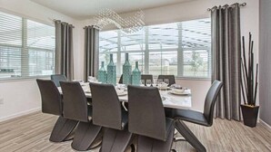 Un espace repas moderne avec une table rectangulaire, six chaises et un luminaire décoratif au plafond.