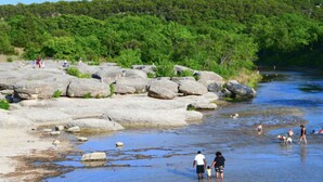 Een rivier met grote rotsen en mensen die langs de oever lopen.
