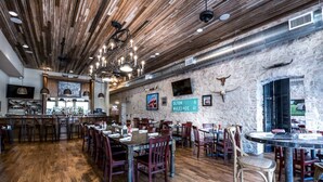 Een restaurant met houten vloeren, een bar en een stenen muur met een bord waarop afstanden naar nabijgelegen steden staan aangegeven.