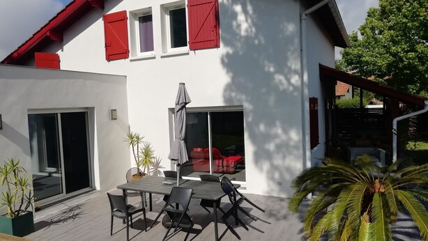 Ett modernt hus med en uteplats, ett matbord och stolar.