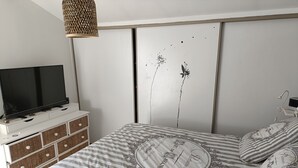 Ett sovrum med en säng, en tv på en byrå och en garderob.