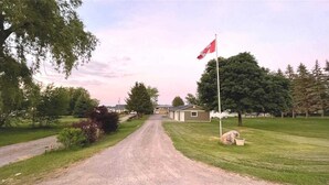 Ein Feldweg führt zu einem Gebäude mit einer Fahnenmast und einer Flagge.