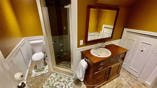 A bathroom with a toilet, shower, sink, and vanity.