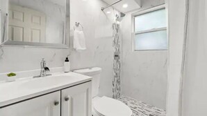 Un baño moderno con tocador, lavamanos e inodoro blancos.
