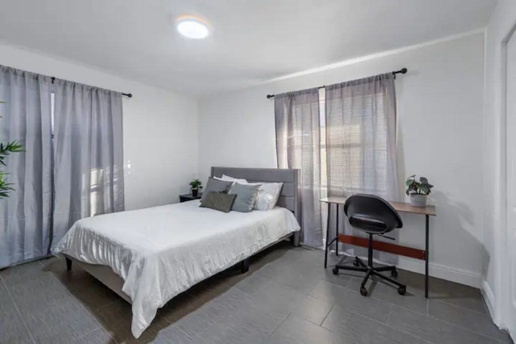 A bedroom with a bed, a desk, and a chair.