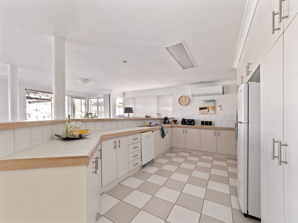 Een moderne keuken met witte kasten, een zwart-wit betegelde vloer en een inbouwkoelkast.
