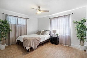 Relax in this serene bedroom with a single bed, ceiling fan, and potted plants.