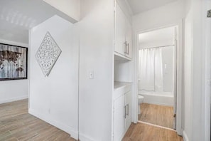 Bathroom features a shower area and white cabinetry.