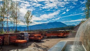 Une terrasse extérieure avec des sièges, un barbecue et un élément décoratif aquatique.