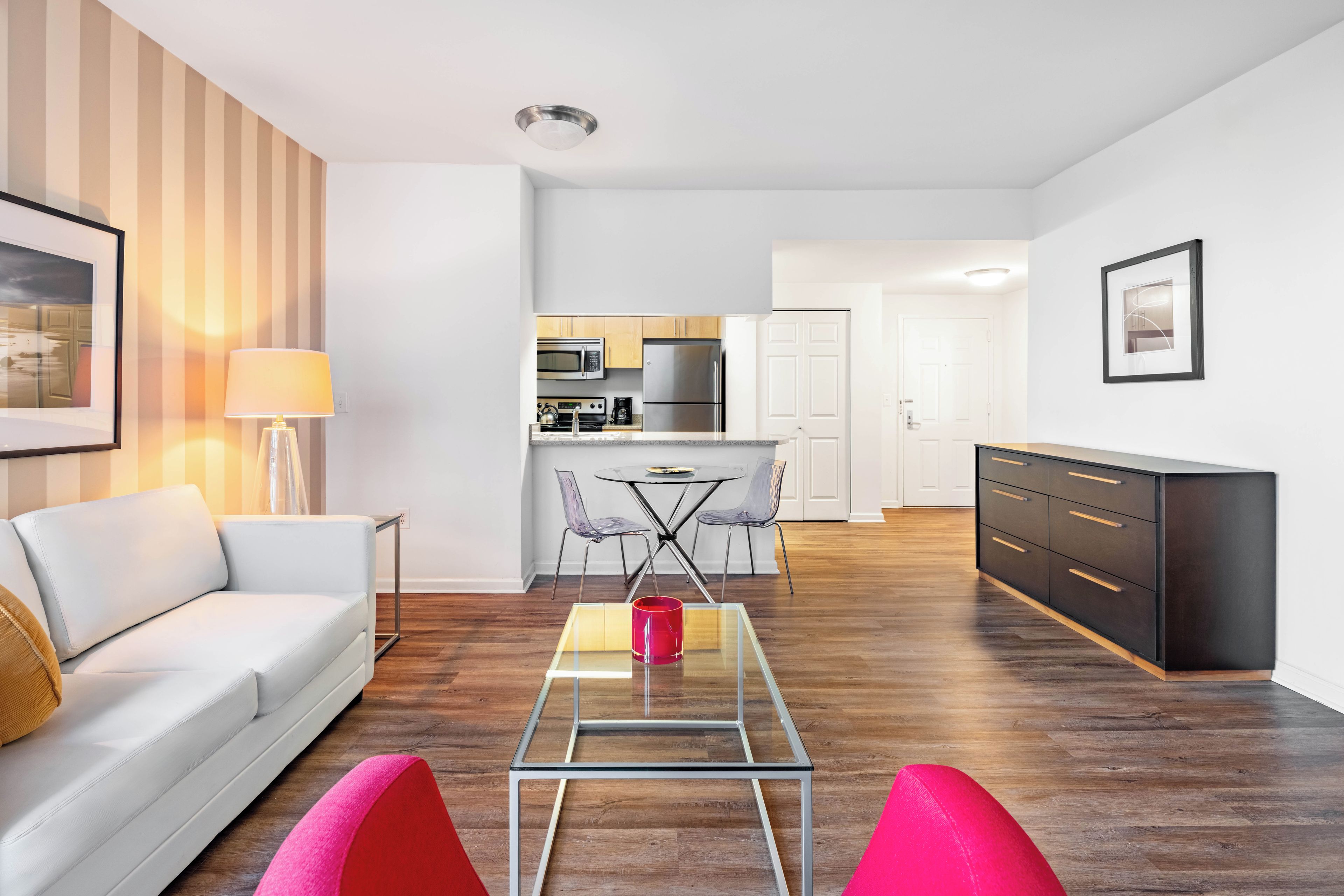 Een moderne woonkamer met een glazen salontafel, een bank en een eetgedeelte met stoelen.